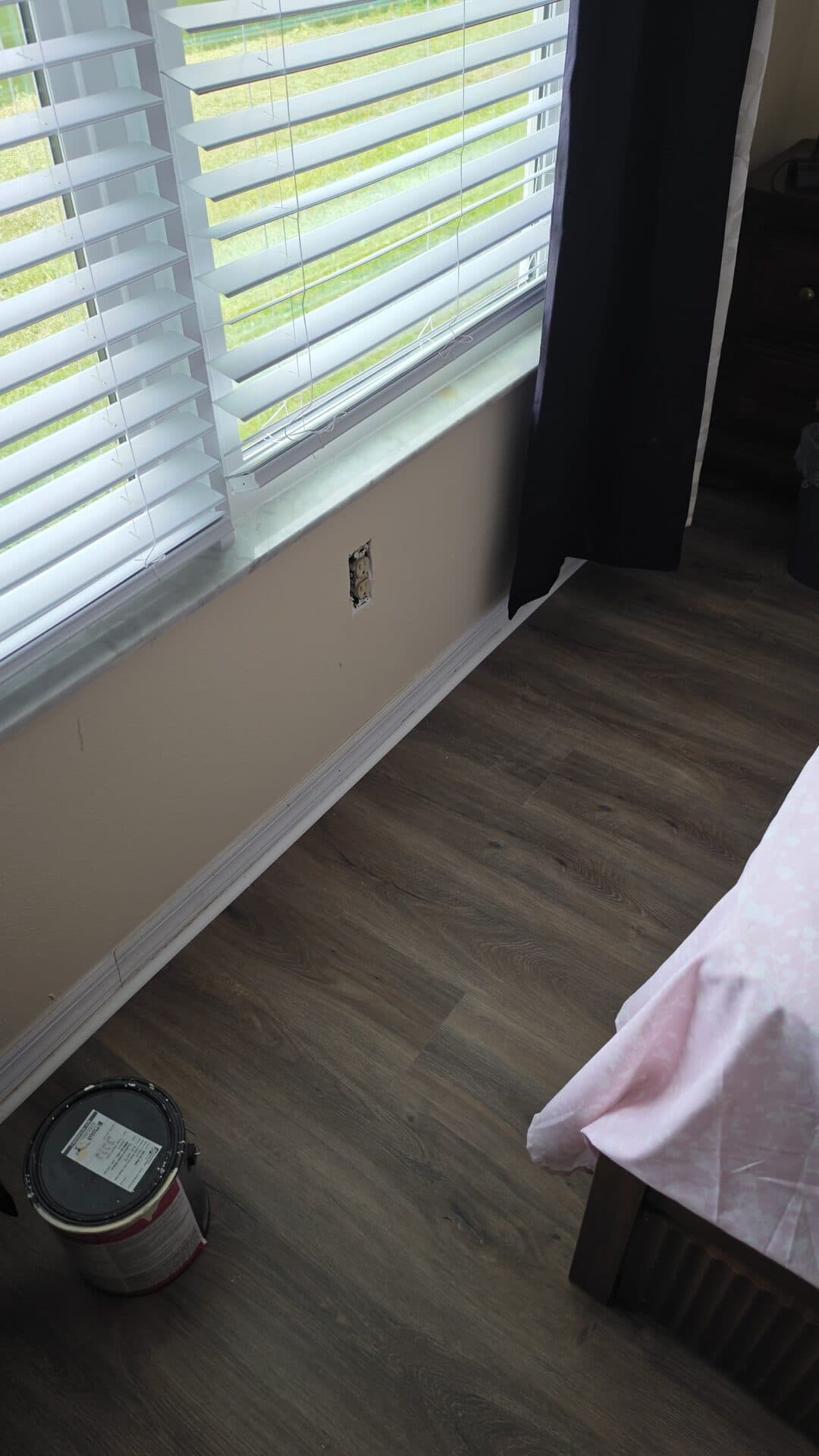 The same window wall finished with paint, new baseboard and quarter round, and new vinyl plank flooring
